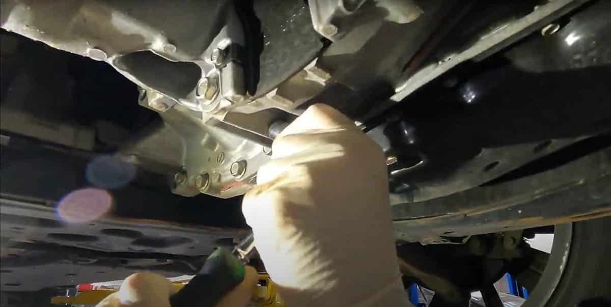 Tommy removing overflow plug to finish service on 2020 Nissan Altima